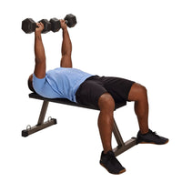 Person exercising with dumbbells for upper body weight workouts on a weight bench against a white background