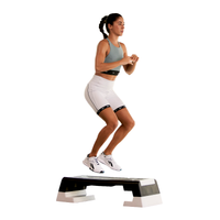 Woman exercising on a step platform against a white background