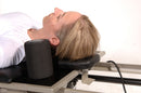 Person using a Pilates reformer machine with a neck pillow.