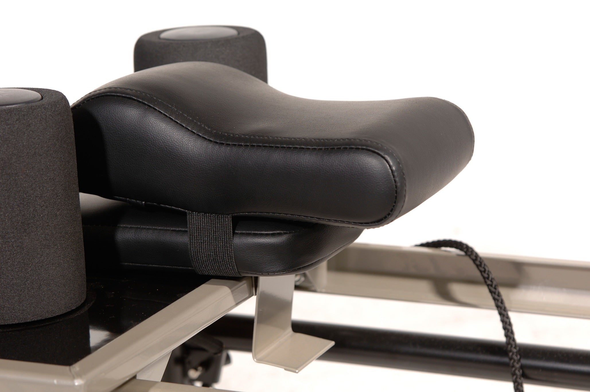 Close-up of a black exercise machine seat on a white background