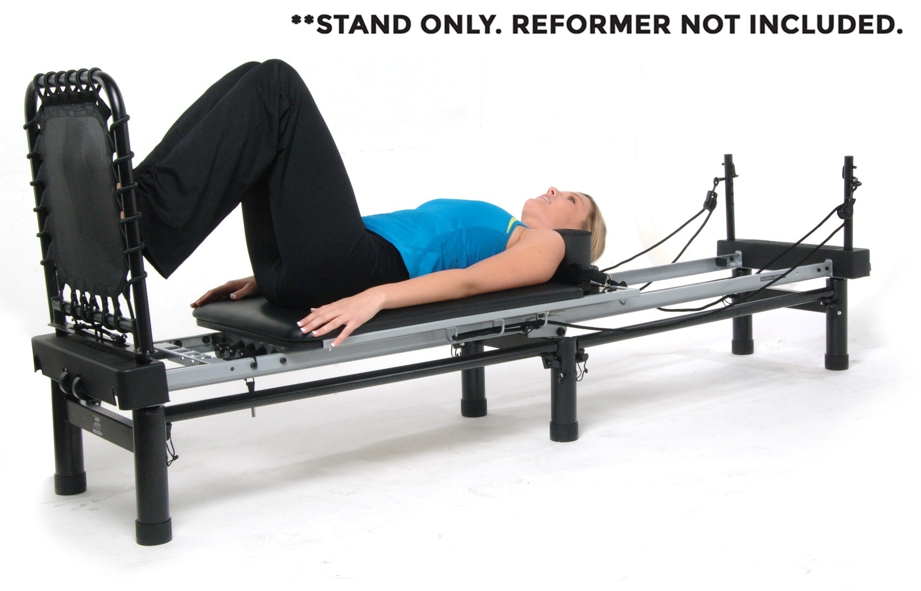 Woman lying on a reformer machine with text indicating reformer not included.