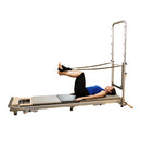 Person using a Pilates reformer machine on a white background