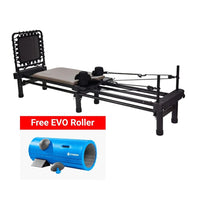 A black Pilates reformer machine with a beige cushioned seat and black handle attachments, shown on a white background with a red promotional banner reading 'Free EVO Roller' 
