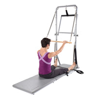 Woman using a Pilates reformer machine on a white background