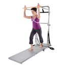 Woman using a Pilates reformer machine on a white background