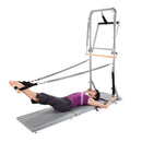 Woman using a Pilates reformer machine on a white background
