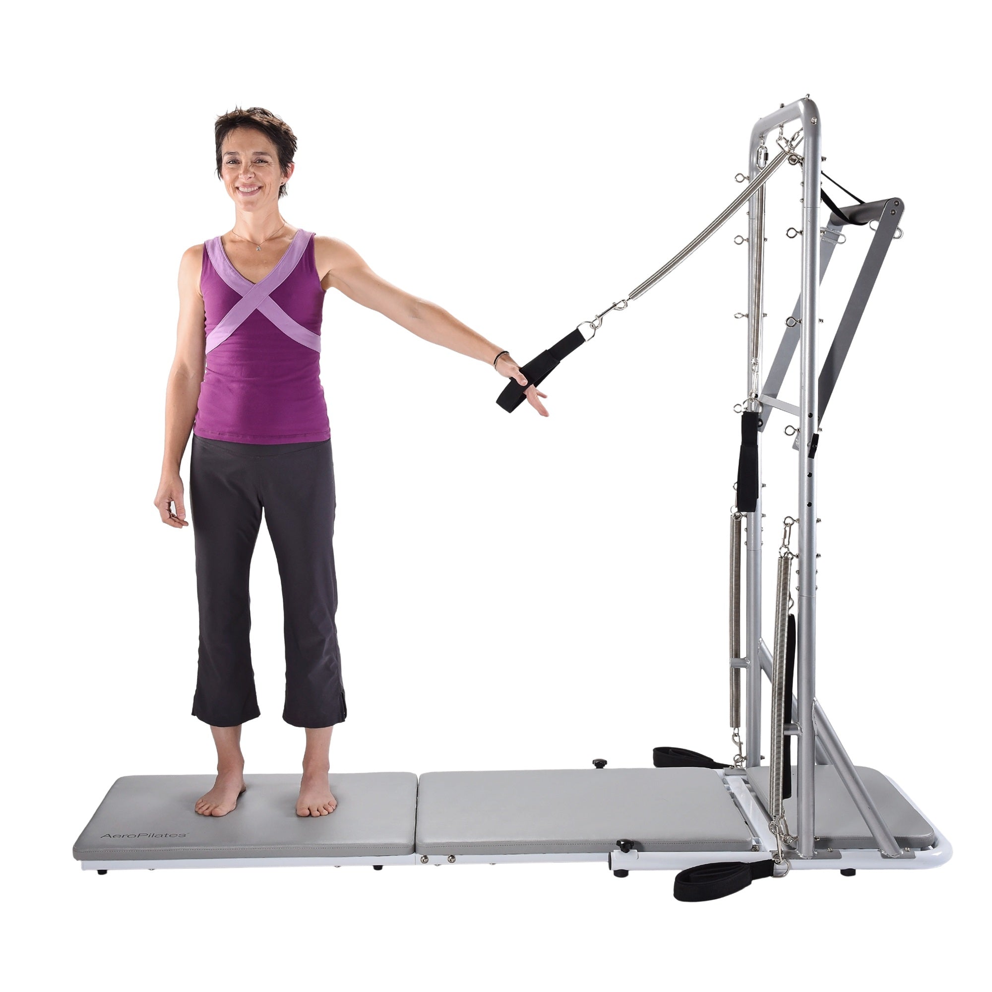 Woman using a Pilates reformer machine on a white background
