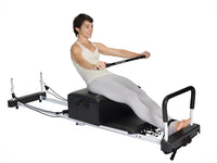 Woman using a Pilates reformer machine on a white background