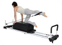 Person using a Pilates reformer machine on a white background