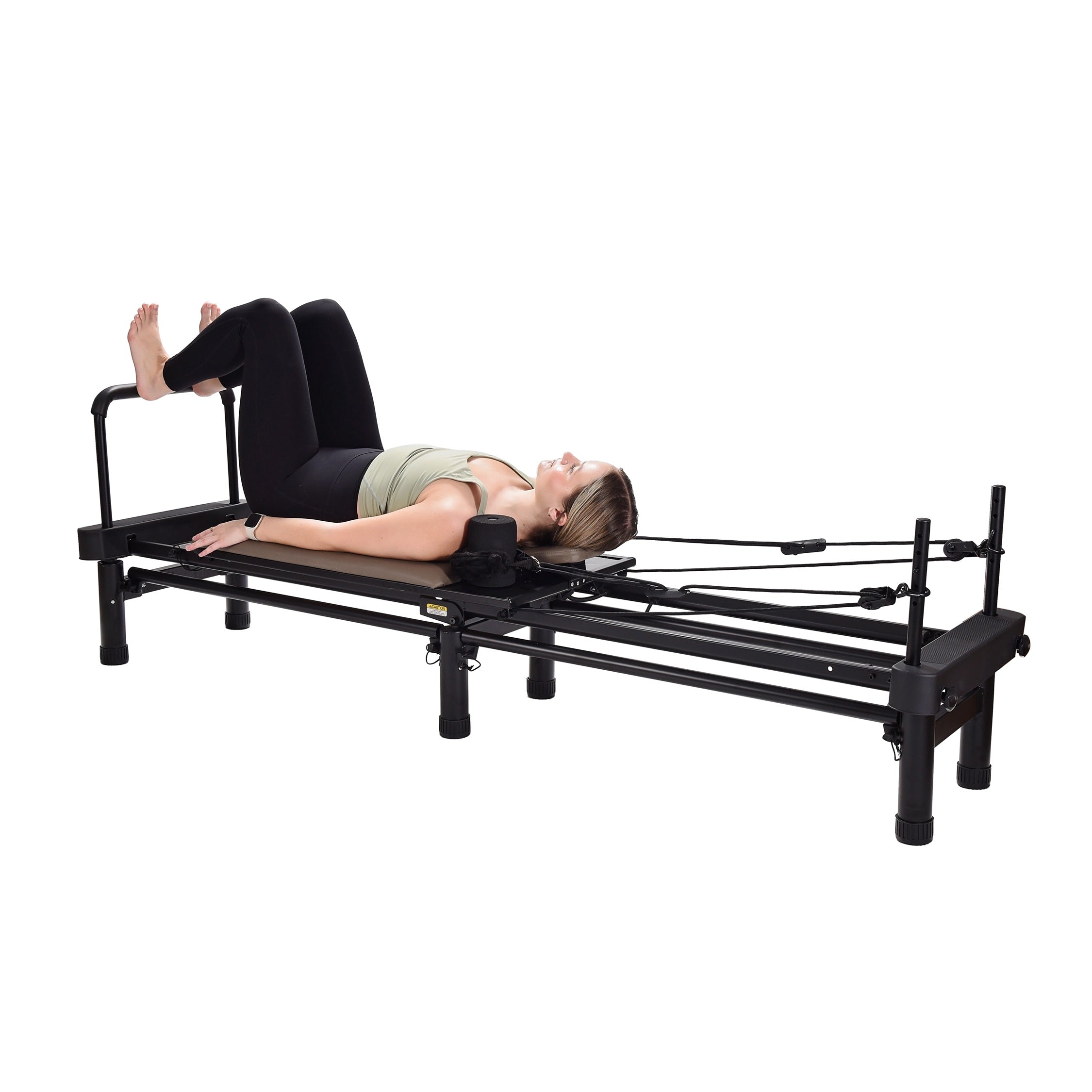 Person using a Pilates reformer machine on a white background