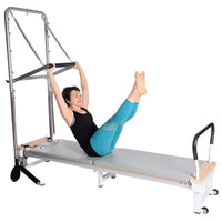 Person using a Pilates reformer machine on a white background