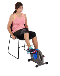 Woman using a mini exercise bike attached to a chair on a white background