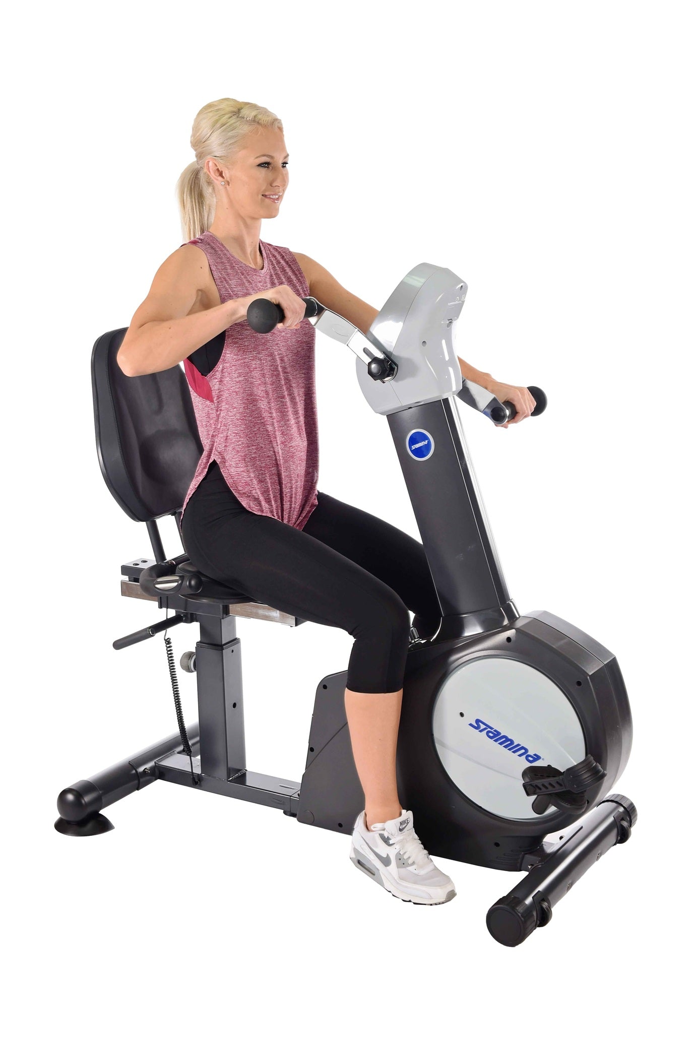 Woman exercising on a Stamina Elite Total Body Recumbent Bike with upper body hand pedals and lower body foot pedals.