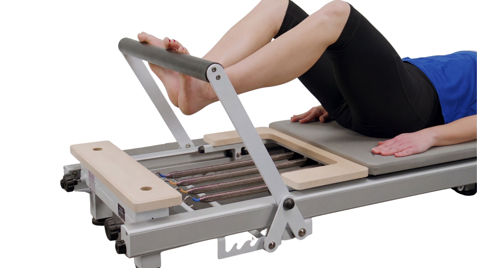 Person using a Pilates reformer machine on a white background