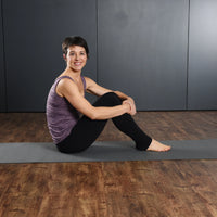 Woman sitting on a yoga mat in a studio setting