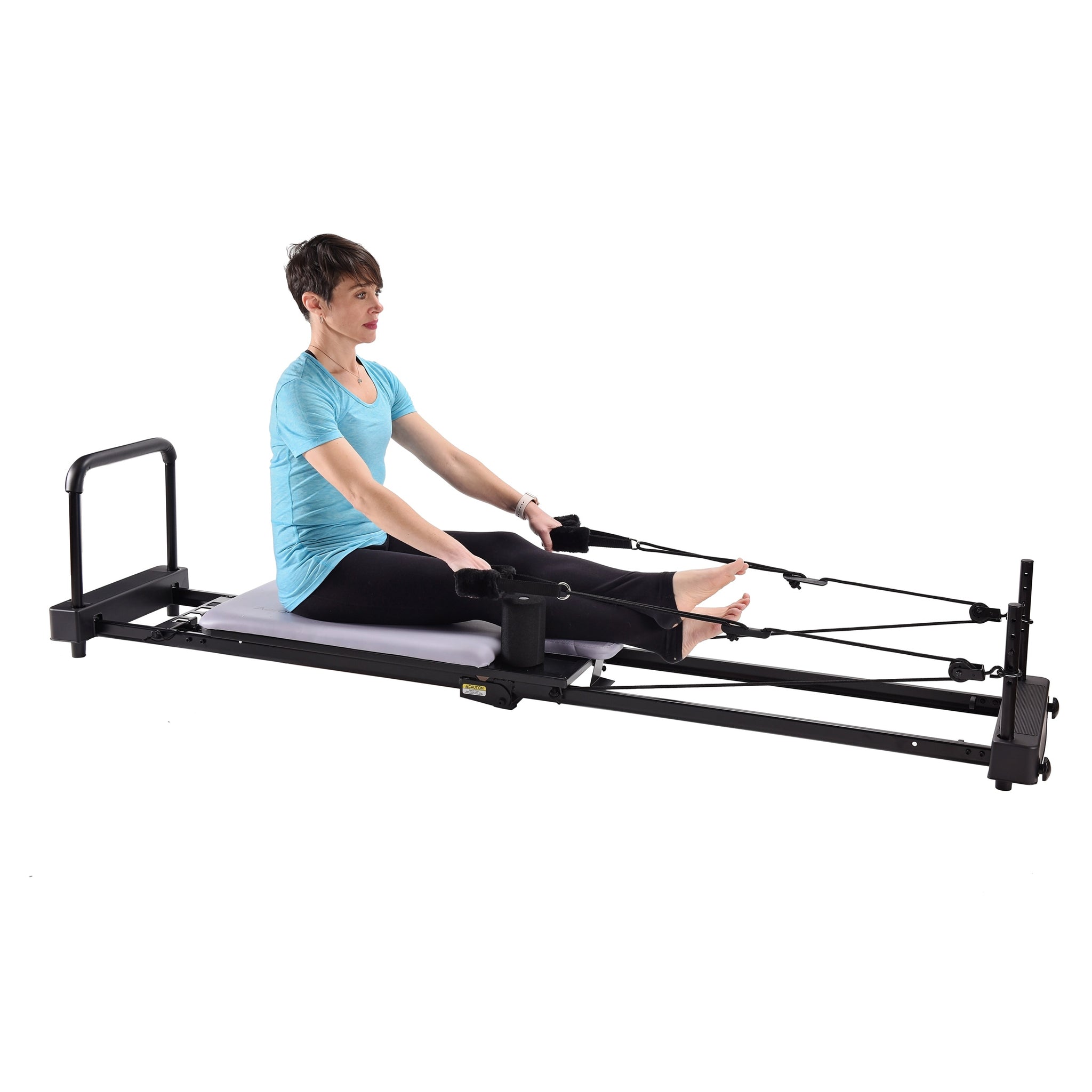 Person using a Pilates reformer machine on a white background