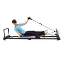 Person using a Pilates reformer machine on a white background