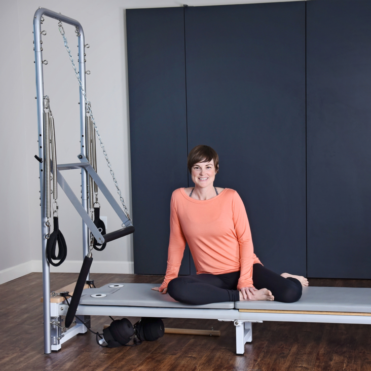 Woman seated on top of the pilates.