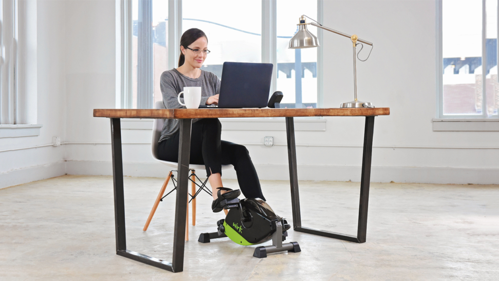 Woman working while using Wirk Under Desk Exercise Bike.