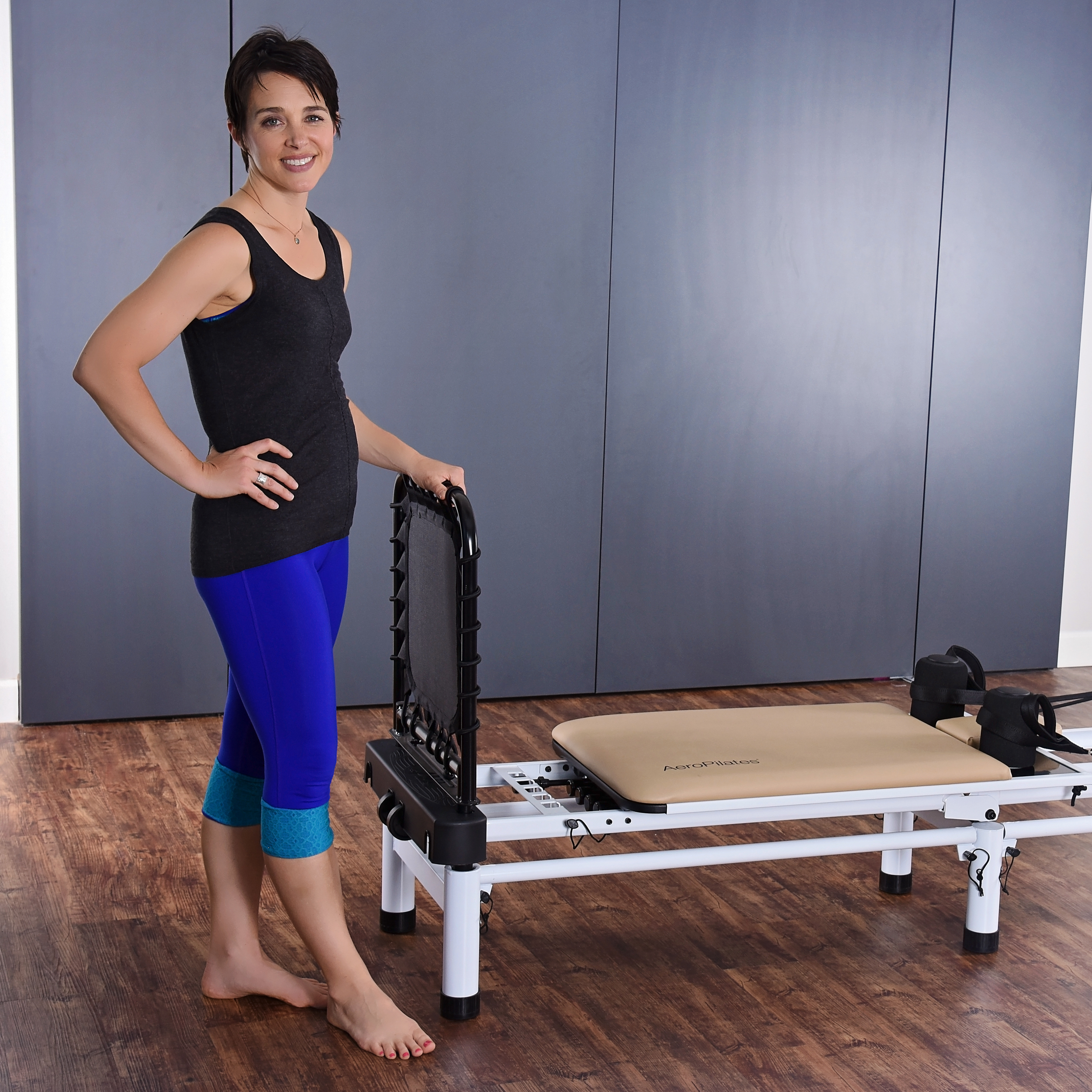Woman standing beside on pilates while holding the cardio rebounder.