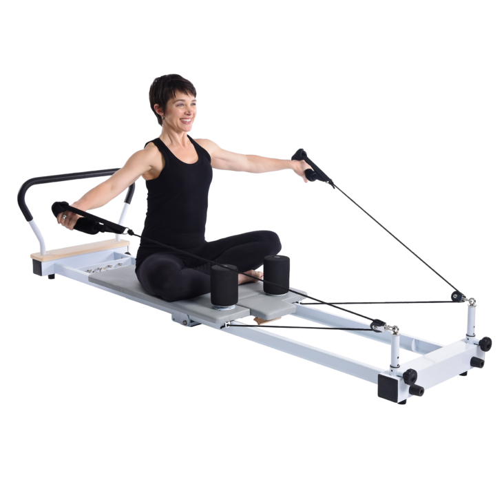 Smiling woman pulling side ward the handstraps on the pilates.