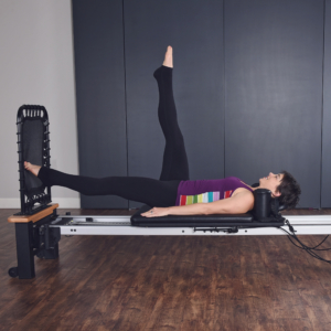 Woman lying down on the pilates and leg bent upward.
