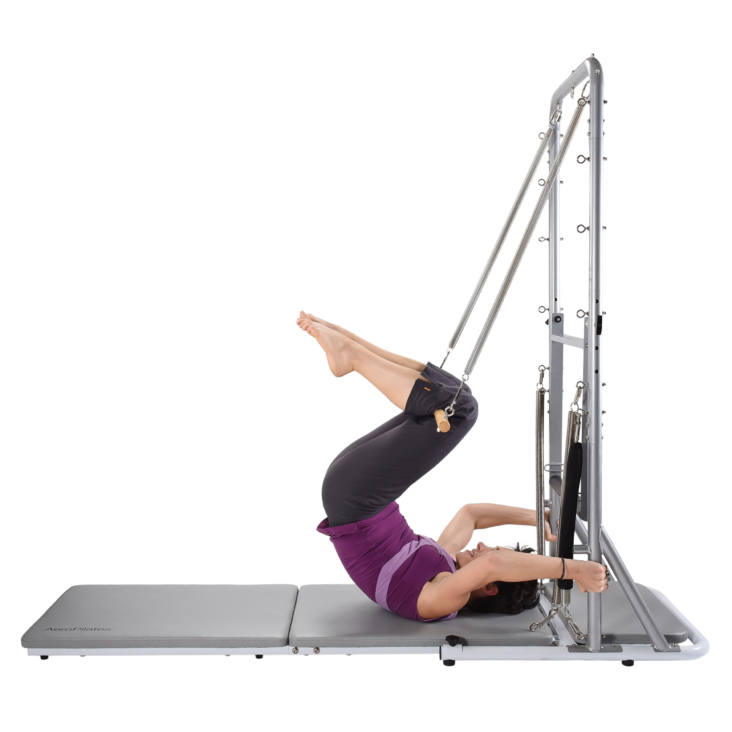 Lying woman lifting back and legs with pilates tower