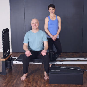 Middle age man and woman sitting and standing on pilates.