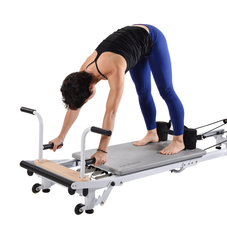 Woman facing downward bending over on pilates equipment