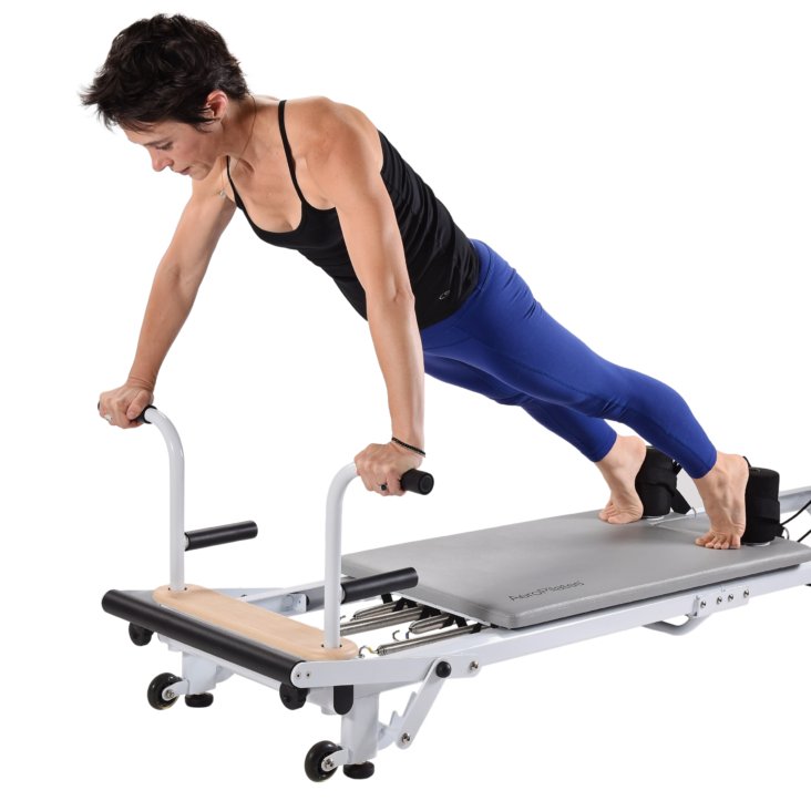 Woman facing downward pushing up on pilates equipment