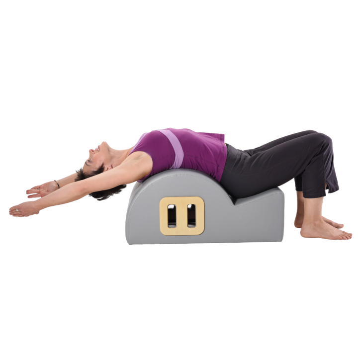 Lying woman stretching arms backwards on spine corrector