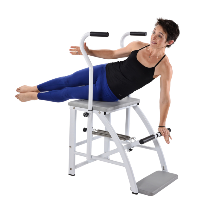 Woman lying on side one arm extended downward on pilates chair