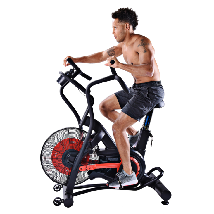 Man seated and arm straight forward while cycling on exercise bike.