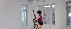 Woman uses Cardio Climber in home gym space.