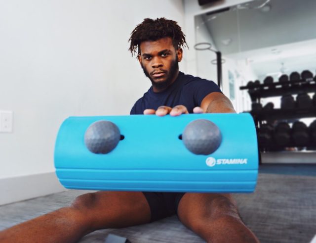 Man holds the EvoRoller, a blue foam roller, out toward the camera.