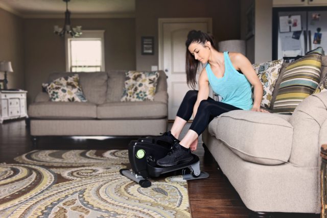 A woman places her feet on a compact strider in her living room.