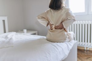 A senior woman touches her back as she experiences sciatic nerve pain.